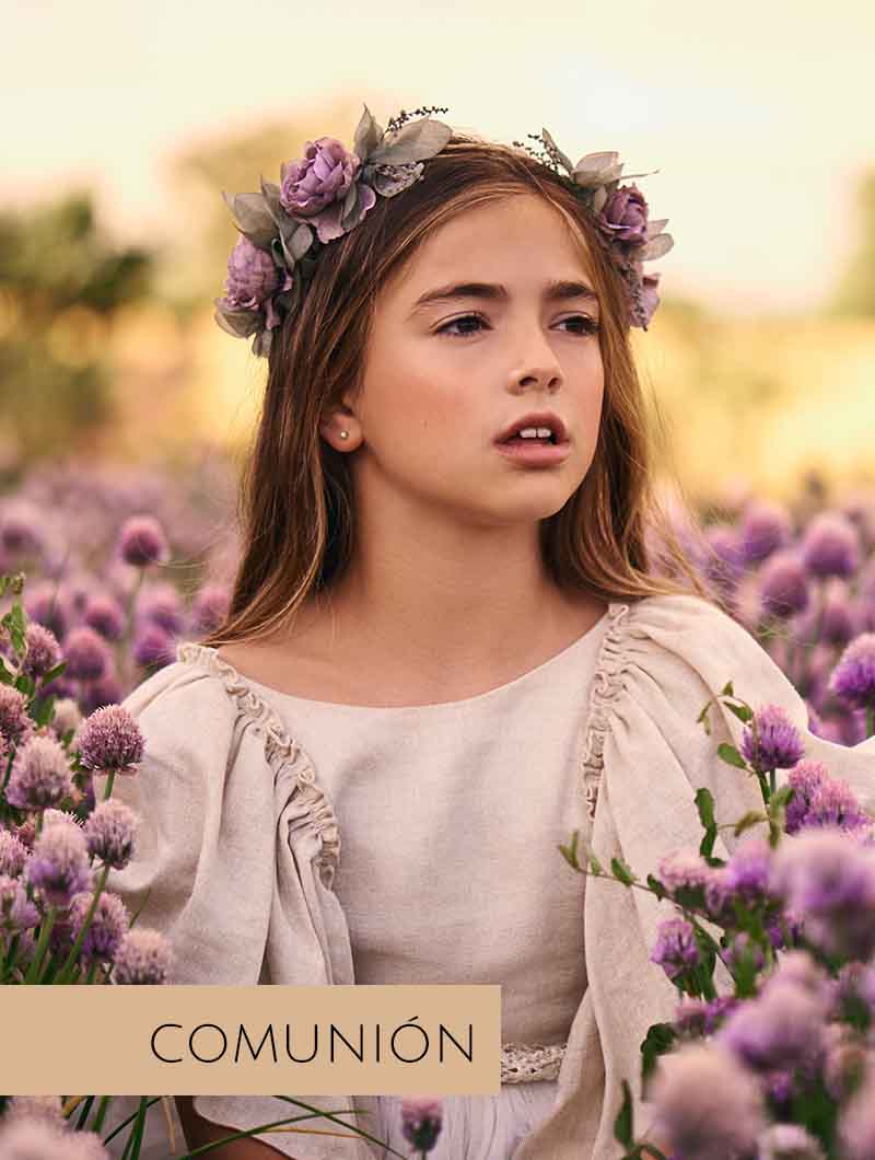 Sesión de fotos en Madrid de niña vestida de comunión al aire libre con flores.