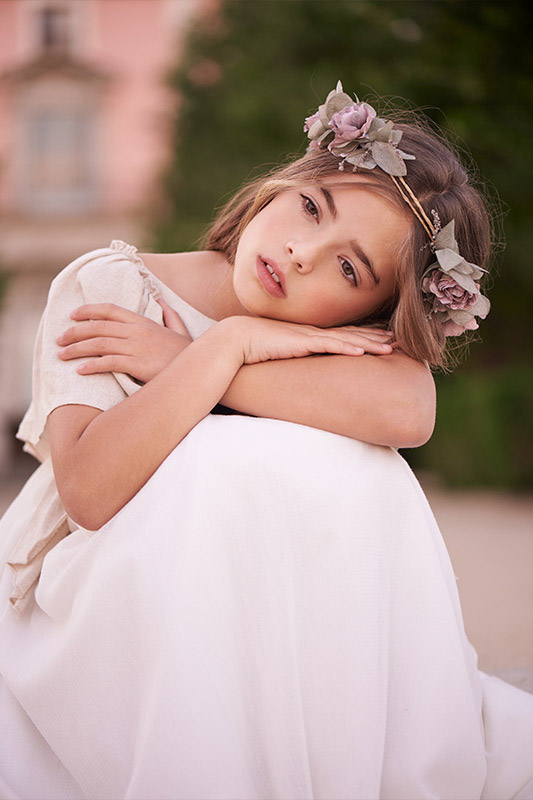 Niña con corona de flores posando para una sesión de fotos de comunión en Madrid.