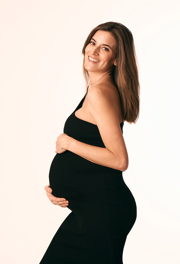 Sesión de fotos de embarazo con vestido negro elegante en Madrid Mujer embarazada con vestido negro posando para una sesión de fotos en Madrid.