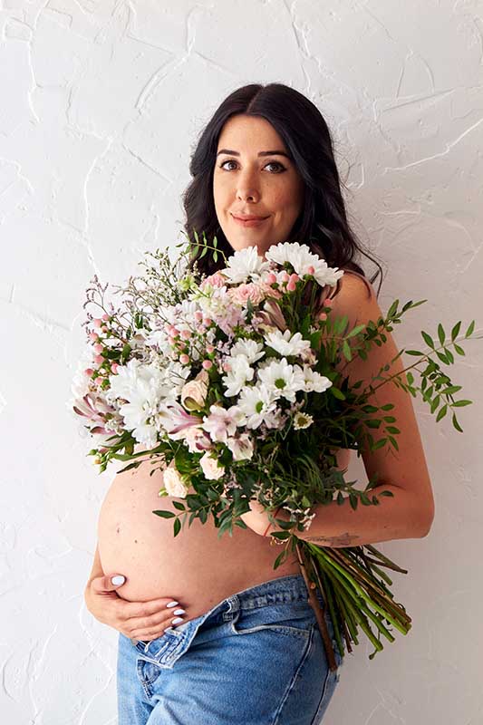 Sesión de fotos de embarazo con ramo de flores en Madrid Mujer embarazada con ramo de flores posando para una sesión de fotos en Madrid.