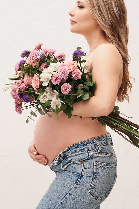 Sesión de fotos de embarazo con ramo de flores en Madrid Mujer embarazada con ramo de flores posando para una sesión de fotos en Madrid.