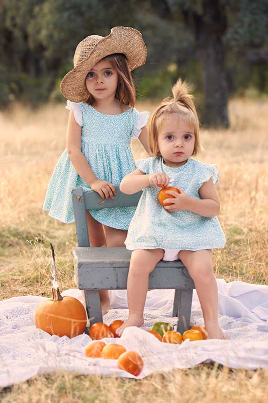 Sesión de fotos de hermanas en picnic en el campo en Madrid Sesión de fotos en el campo en Madrid de hermanas con vestidos azules y calabazas.
