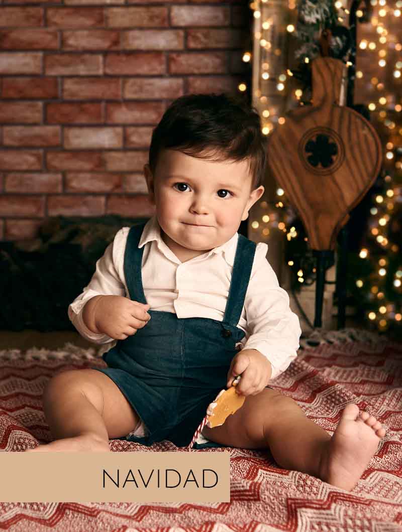Sesión de fotos navideñas en Madrid con niño frente a árbol de Navidad decorado.