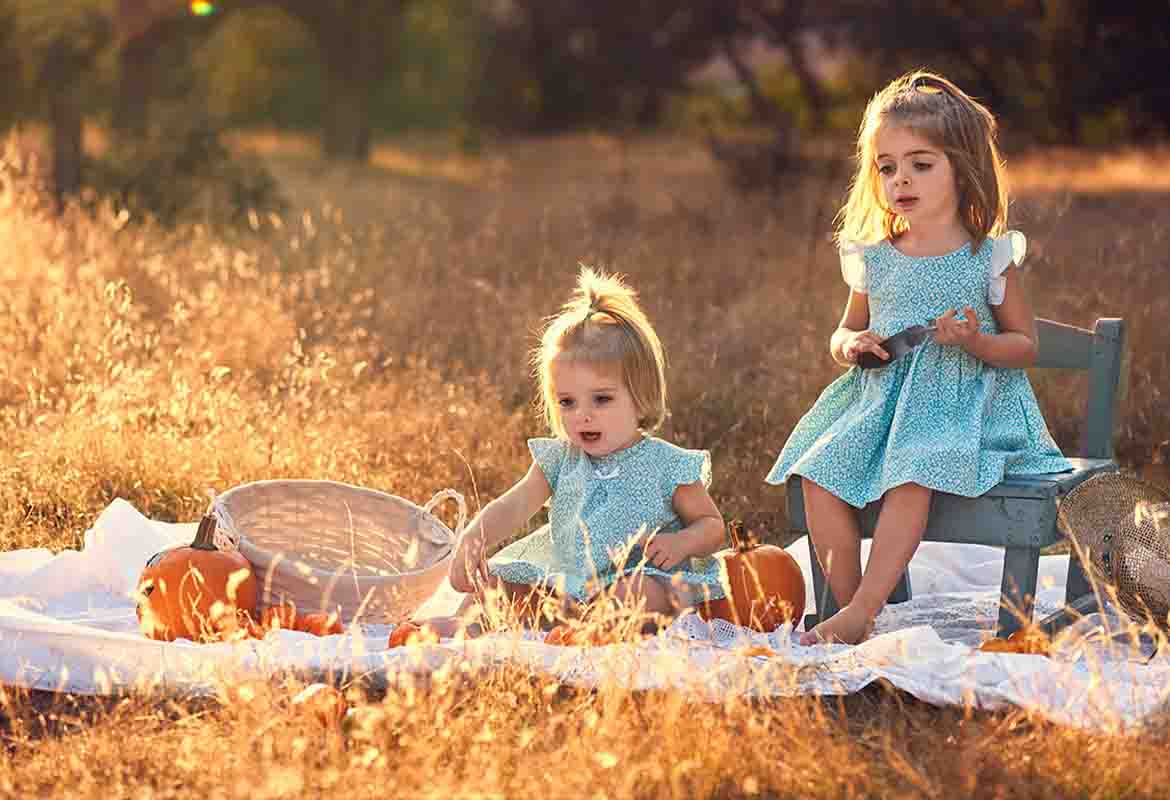 Sesión de fotos de niñas jugando en el campo en Madrid Sesión de fotos en el campo en Madrid de niñas jugando con calabazas al atardecer.
